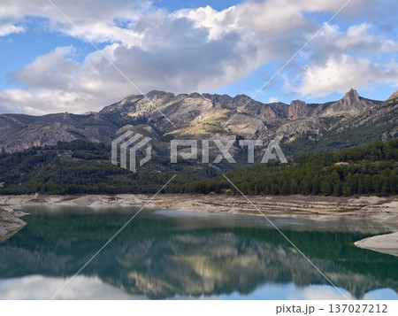 Scenic mountain scene, Breathtaking mountain range with sparkling reservoir and sunlit ridges Scenic mountain scene, Breathtaking mountain range with sparkling reservoir and sunlit ridges 137027212