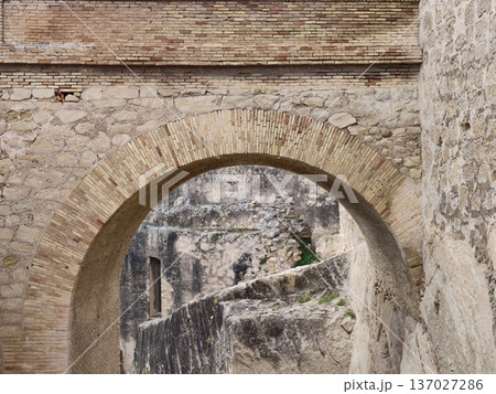 Ancient fort corridor with figure, Historic rampart corridor with distant figure and textured stones 137027286