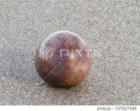 Detailed view of rusty metallic sphere on coarse sand with gentle shadows and minimalist aesthetic Detailed view of rusty metallic sphere on coarse sand with gentle shadows and minimalist aesthetic 137027369