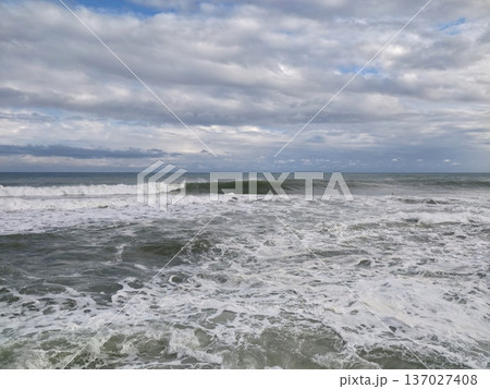 Wave approaching shoreline, Solitary crest surging forward through rippling textured waters with foam Wave approaching shoreline, Solitary crest surging forward through rippling textured waters with foam 137027408