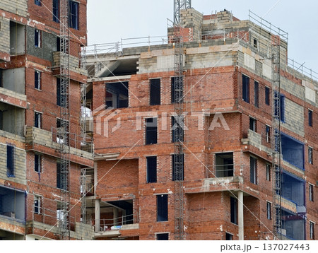 An unfinished red brick edifice showcasing open window spaces and overcast weather backdrop An unfinished red brick edifice showcasing open window spaces and overcast weather backdrop 137027443