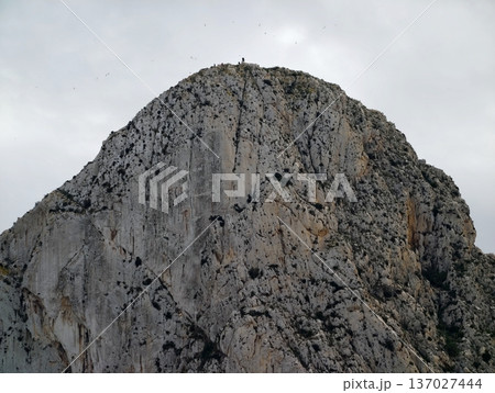 Rugged peak under cloudy sky, Silent elevated mountain with shadowed ledges and muted illumination 137027444
