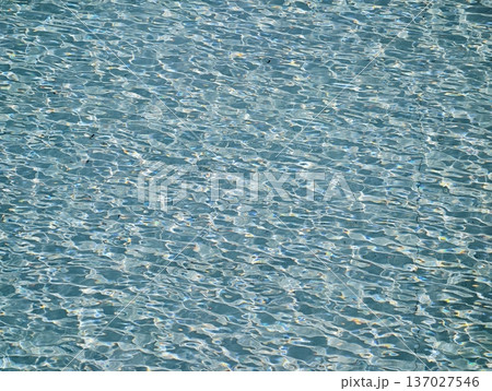 Bright sunlit turquoise pool rippling with shimmering reflections perfect for summer and wellness imagery 137027546