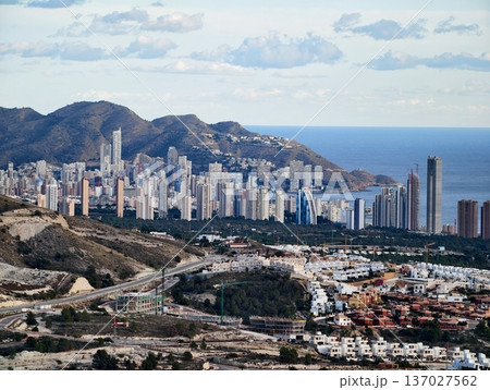 Cityscape with mountains and water, Vertical city growth rising against rocky terrains by waterfront Cityscape with mountains and water, Vertical city growth rising against rocky terrains by waterfront 137027562