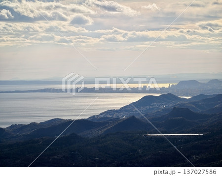 Dramatic ridge under cloudy sky, Moody panoramic view of rugged coast with textured terrain Dramatic ridge under cloudy sky, Moody panoramic view of rugged coast with textured terrain 137027586