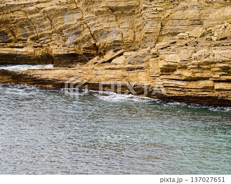 Quiet bay with layered rocks, Horizontal banded sandstone overlooking peaceful bay surface and warmth 137027651