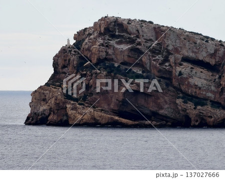 Rough cliffs meet tranquil waters, Jagged cliffs intersect smooth water with visible erosion features 137027666