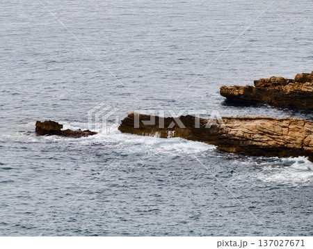 Foamy surf with broken reef stones, Wet textured stones amid breaking waves and coastal shallow reefs 137027671