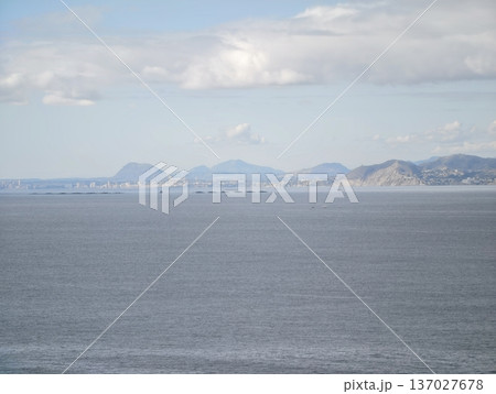 Serene coastal scenery, Gentle clouds cast soft shadows over lofty peaks surrounding calm and silent sea Serene coastal scenery, Gentle clouds cast soft shadows over lofty peaks surrounding calm and silent sea 137027678
