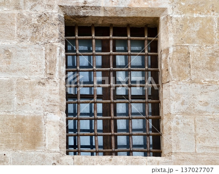 Industrial style window with reflections, Stoneframed window featuring reflective glass and iron bars Industrial style window with reflections, Stoneframed window featuring reflective glass and iron bars 137027707