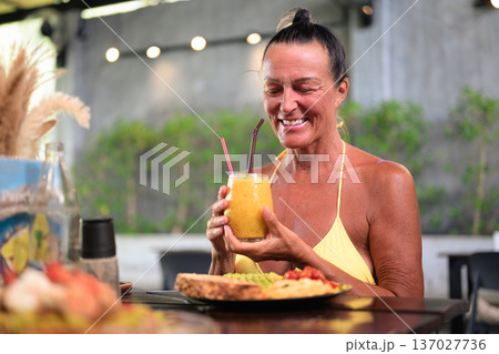 Happy Mature Woman Enjoying Healthy Breakfast Outdoors in Coffee Shop 137027736
