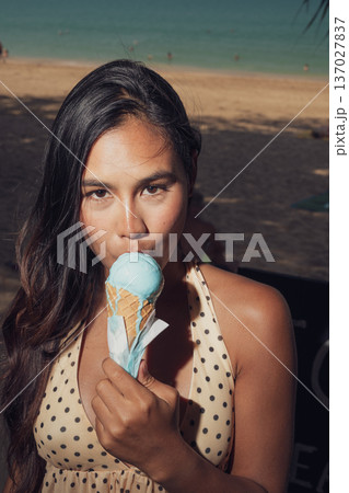 Close-up portrait of smiling woman holding melting ice cream on sunny beach Close-up portrait of smiling woman holding melting ice cream on sunny beach 137027837