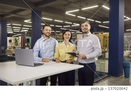 Young couple standing at building market with salesman helping them to make purchase in hypermarket Young couple standing at building market with salesman helping them to make purchase in hypermarket 137028642