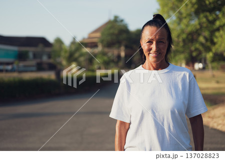Smiling Mature Scandinavian Tourist Woman Walking Outdoors on Summer Holiday Smiling Mature Scandinavian Tourist Woman Walking Outdoors on Summer Holiday 137028823