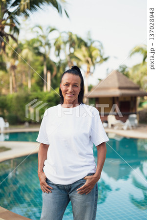 Smiling beautiful older Scandinavian tourist woman standing near swimming pool during holiday 137028948
