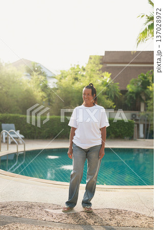 Full length portrait of mature Scandinavian woman standing near swimming pool in Thailand 137028972