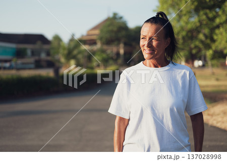 Smiling Mature Scandinavian Tourist Woman Walking Outdoors on Summer Holiday Smiling Mature Scandinavian Tourist Woman Walking Outdoors on Summer Holiday 137028998