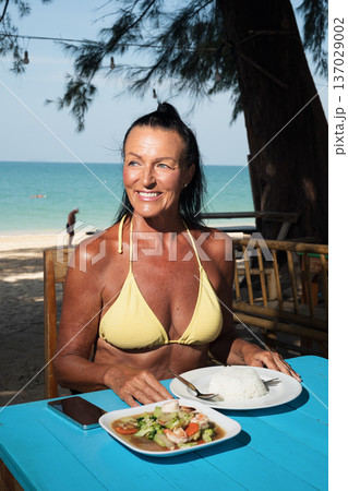 Active senior woman enjoying seafood and rice at seaside restaurant in Thailand cafe restaurant Active senior woman enjoying seafood and rice at seaside restaurant in Thailand cafe restaurant 137029002