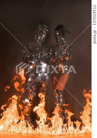Dancers in reflective costumes performing amidst flames at a night event Dancers in reflective costumes performing amidst flames at a night event 137029512