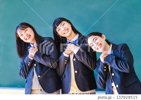 黒板の前で友達とポーズをとる女子高生 137029515