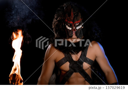 Dramatic performance featuring a masked warrior holding a torch at night Dramatic performance featuring a masked warrior holding a torch at night 137029619