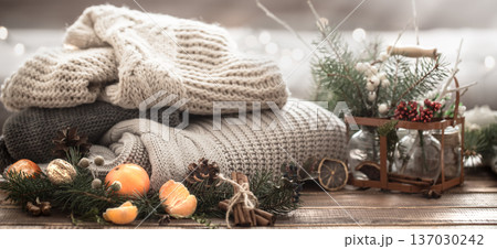 Christmas still life of a live Christmas tree, decorations and festive wreath on a background of knitted clothes 137030242