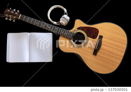 Classical acoustic guitar, headphones and notebook on a black background. Classical acoustic guitar, headphones and notebook on a black background. 137030501