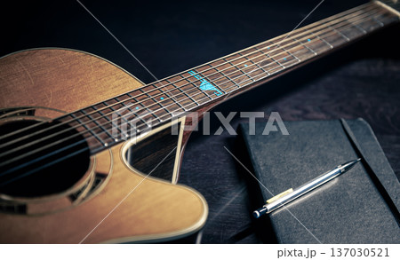 Close-up, acoustic guitar and notepad on a dark background. Close-up, acoustic guitar and notepad on a dark background. 137030521
