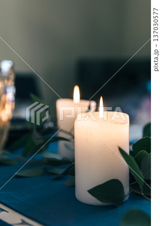 Close-up, burning candles on the table among the leaves. Close-up, burning candles on the table among the leaves. 137030577