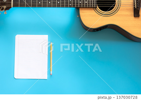 Acoustic guitar and blank paper on blue background, top view. 137030728