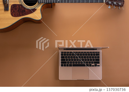 Acoustic guitar and laptop on a brown background, top view, copy space. 137030736
