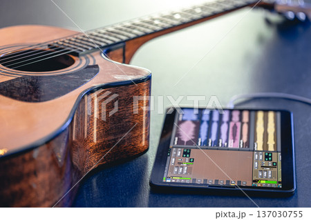 Acoustic guitar and tablet on the table, music recording concept. Acoustic guitar and tablet on the table, music recording concept. 137030755