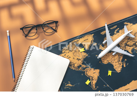 An airplane miniature, notebook and world map on brown background, flat lay. 137030769