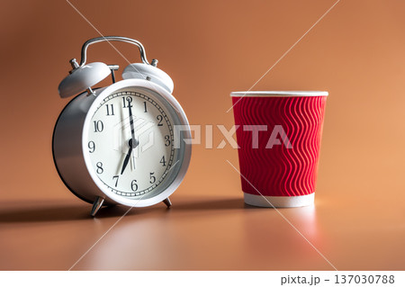 Alarm clock and paper disposable cup of coffee. Alarm clock and paper disposable cup of coffee. 137030788
