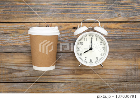 Alarm clock and paper disposable glass on wooden background. Alarm clock and paper disposable glass on wooden background. 137030791
