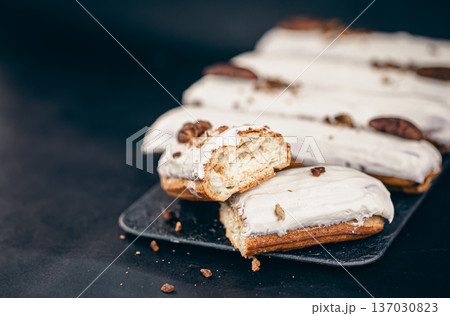 Close-up of eclairs in white glaze with pecans. Close-up of eclairs in white glaze with pecans. 137030823