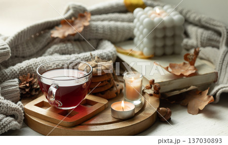 Autumn still life with a cup of tea, candles, cookies and a knitted elements. Autumn still life with a cup of tea, candles, cookies and a knitted elements. 137030893