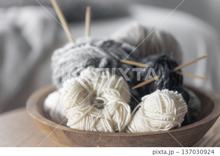 Balls of thread in a wooden mouse on the table.Home hobby of knitting and needlework. Home comfort. Balls of thread in a wooden mouse on the table.Home hobby of knitting and needlework. Home comfort. 137030924