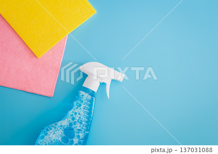 Blank cleaning spray bottle and colored rags on blue background, flat lay. Blank cleaning spray bottle and colored rags on blue background, flat lay. 137031088