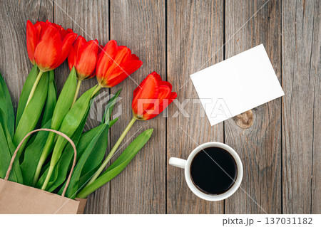Bouquet of red tulips, a cup of coffee and a blank sheet, space for text. 137031182