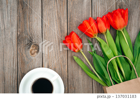 Bouquet of red tulips and a cup of coffee on a wooden background, top view. 137031183
