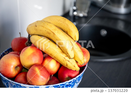 A bunch of bananas and apples in the kitchen near the sink. A bunch of bananas and apples in the kitchen near the sink. 137031220