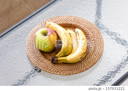 A bunch of bananas and apples in a plate in the interior of the room. A bunch of bananas and apples in a plate in the interior of the room. 137031221