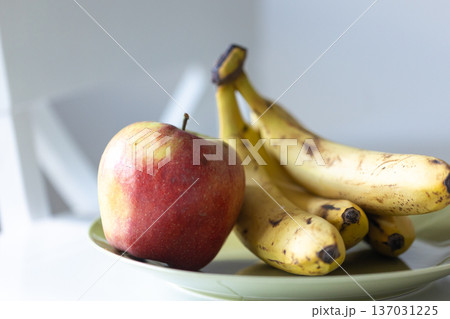 A bunch of ripe bananas and an apple on the kitchen table. 137031225