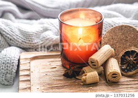 Burning candle and cookies on a blurred background with a knitted element. 137031256