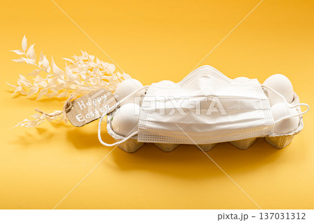 Easter composition with a tray of eggs wearing a protective mask. 137031312