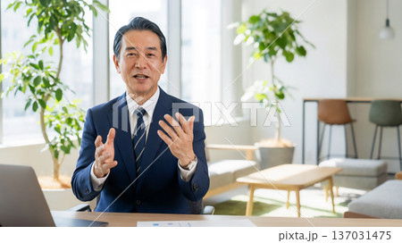 明るいオフィスで身振り手振りを使って真剣に話す中年日本人ビジネスマン 明るいオフィスで身振り手振りを使って真剣に話す中年日本人ビジネスマン 137031475