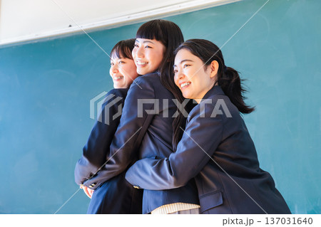 黒板の前で友達とポーズをとる女子高生 137031640