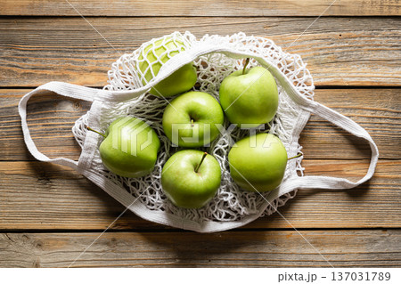 Close-up, green apples in a mesh shopping bag, top view. Close-up, green apples in a mesh shopping bag, top view. 137031789