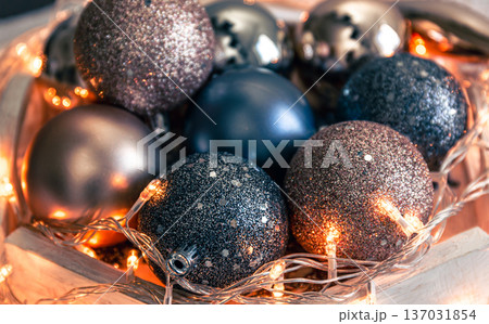 Close-up, shiny Christmas balls and a garland on a wooden stand. 137031854